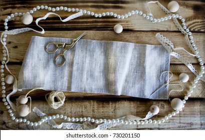 Vintage style background with scissors, thread, lace, wooden beads, pearls, needle for handmade on wooden surface - Powered by Shutterstock