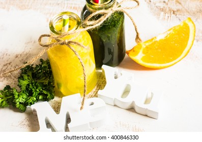 Vintage style bottles with fresh organic orange and green spinach smoothie on wooden table