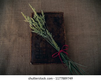 Vintage Style. Closed Antique Book With Dry Grass And Red Thread With Burlap Background