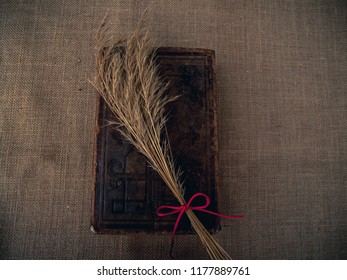 Vintage Style. Closed Antique Book With Dry Grass And Red Thread With Burlap Background