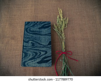 Vintage Style. Closed Antique Book With Dry Grass And Red Thread With Burlap Background