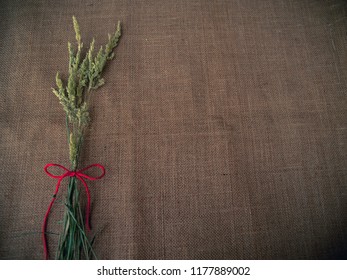 Vintage Style. Dry Grass And Red Thread With Burlap Background