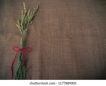 Vintage Style. Dry Grass And Red Thread With Burlap Background