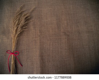 Vintage Style. Dry Grass And Red Thread With Burlap Background