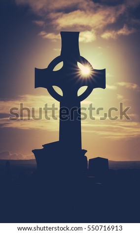 Vintage Style Image Of Sun Glinting Through A Celtic Cross Gravestone