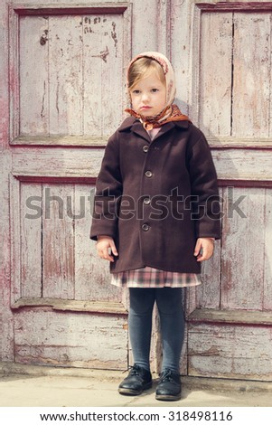 Vintage style. Little cute girl on the background of the old door. Selective focus.