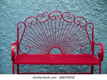 The Vintage Style Of Metal Red Long Chair And Background Of Rough Cement Wall Painting  With Pastel Blue Color, Concept Of Exterior Decoration.