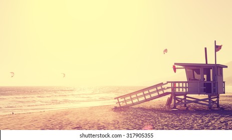 Vintage style picture of lifeguard tower at sunset in Malibu, lens flare effect, USA.