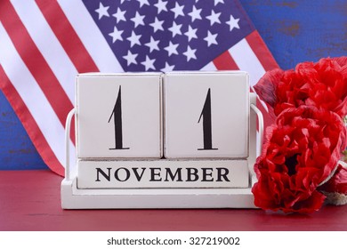 Vintage style wood block calendar for November 11, USA Veterans Day, with Stars and Stripes flag  and red Flanders poppy flowers for remembrance on red and blue wood background. 