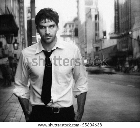 Vintage stylized black and white photo of young male model against city street (Photo has an intentional film grain)