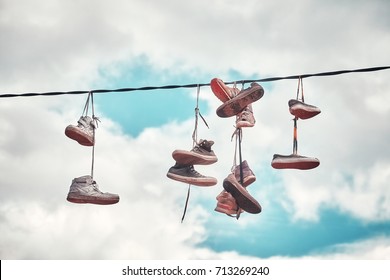 Vintage Stylized Picture Of Old Dirty Shoes Hanging On Wire.