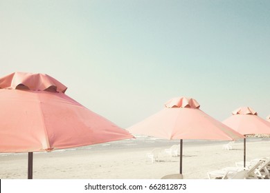 Vintage summer beach with pink pastel parasols