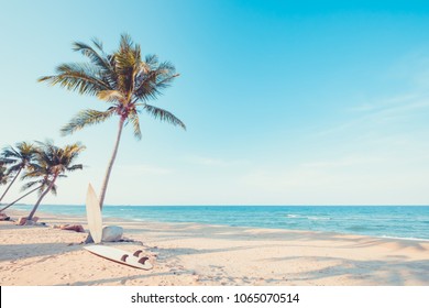 Винтажная доска для серфинга с пальмой на тропическом пляже летом. Винтажный цветовой тон
