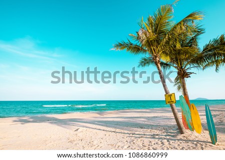 Vintage surf board with palm tree on tropical beach in summer. vintage color tone