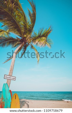 Vintage surf board with palm tree on tropical beach in summer. vintage color tone