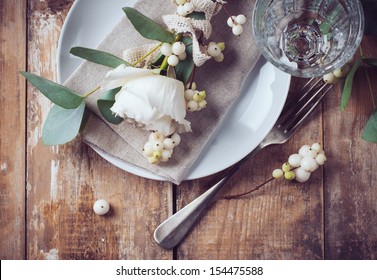 Vintage table setting with floral decorations, napkins, white roses, leaves and berries on a wooden board background - Powered by Shutterstock