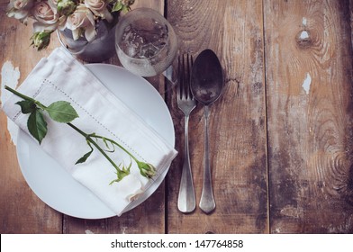 Vintage table setting with roses, antique rustic dishes and cutlery on the wooden background, close-up - Powered by Shutterstock