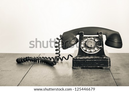 Vintage telephone on old table sepia photo