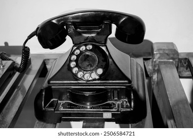 Vintage telephone on an old wooden table. Old black retro rotary Telephone in vintage style. An old fashioned landline phone. Objects that make nostalgic, sentimental yearning for a past period