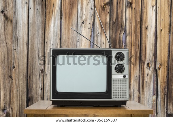 Vintage\
television on table with rustic wood wall. \

