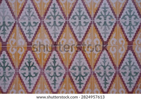Vintage tile pattern with ornate, repeating geometric designs. Warm tones of yellow, green, and red create rich visual texture. Each tile features stylized floral and diamond motifs