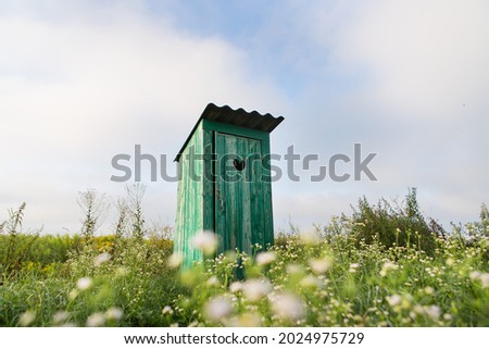 Vintage toilet. An outdoor rustic green toilet with a heart cut out on the door. Toilet in a field of flowers ストックフォト © 