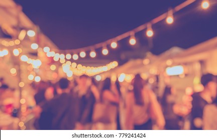 vintage tone blur image of food stall at night festival with bokeh for background usage .