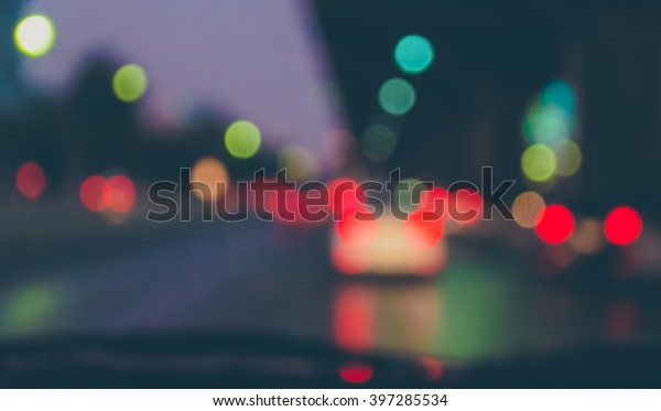 vintage tone blur image of\
inside cars with bokeh lights from traffic jam on night time for\
background.