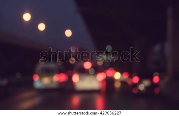 vintage tone blur image of\
inside cars with bokeh lights from traffic jam on night time for\
background.