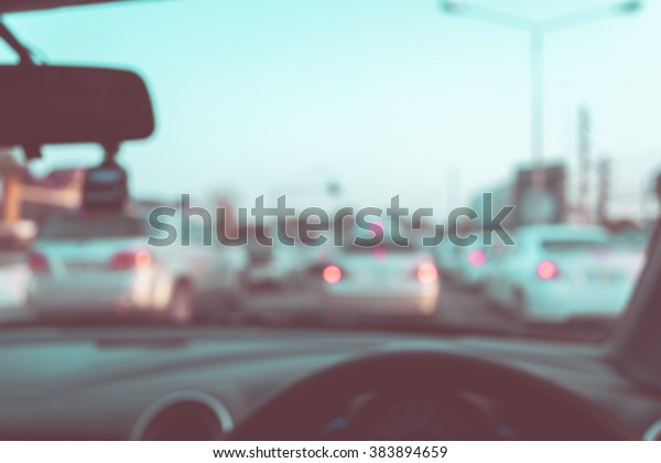 vintage tone blur image of\
people driving car on day time for background usage.(take photo\
from inside)