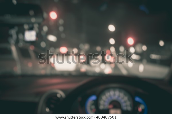 vintage tone blur image of\
people driving car on night time for background usage.(take photo\
from inside)