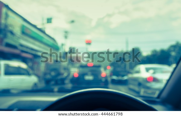 vintage tone blur image of\
people driving car on day time for background usage.(take photo\
from inside)