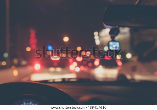 vintage tone blur image of\
people driving car on night time for background usage.(take photo\
from inside)
