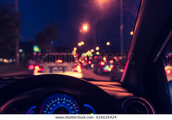 vintage tone blur image of
people driving car on night time for background usage.(take photo
from inside)