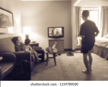 Vintage Tone Blurred Image Rear View Of An Asian Family Relaxing On A Sofa And Watching TV At American Hotel