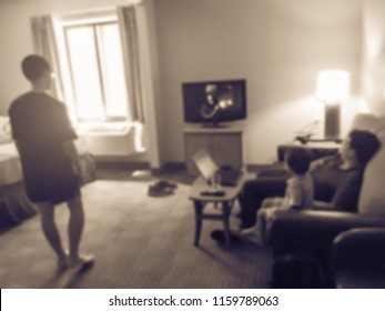 Vintage Tone Blurred Image Rear View Of An Asian Family Relaxing On A Sofa And Watching TV At American Hotel