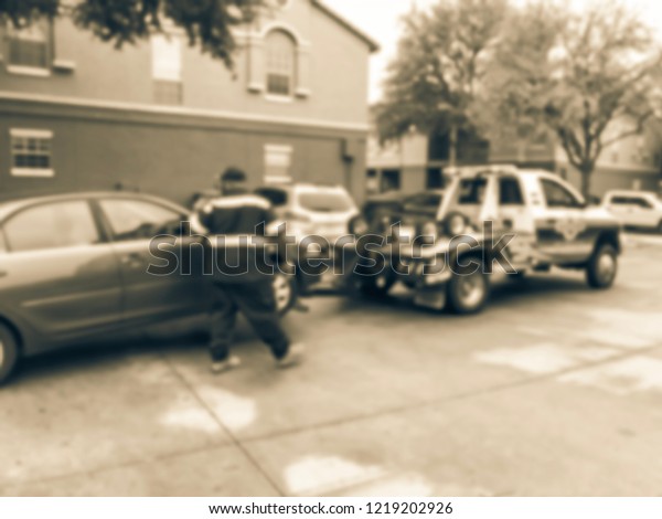 Vintage tone blurred\
motion damaged car being towed by truck to mechanic shop from\
apartment building complex. Insurance theme concept, roadside\
assistance accident\
support