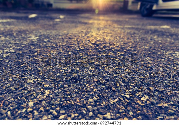 vintage tone image of damaged crack asphalt\
street day time with car in\
background.
