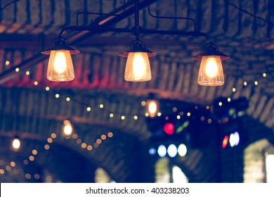 Vintage Tone Image Of Lights On A Cement Ceiling Archway In A Barn Set Up For A Wedding Reception.