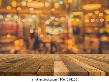 vintage tone image of selective focus on surface of wood table and blur restaurant for background usage.