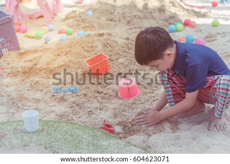 vintage tone image of young asian boy playing in sand pit day time.