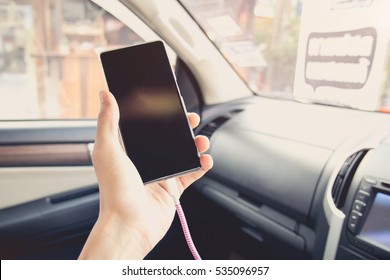 Vintage Tone Picture Of Close-up Man Driver Using And Charging Smart Phone  In Car