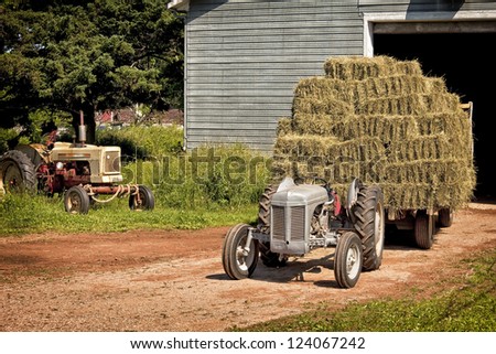 Vintage tractor hauling a wagon load of hay bales.