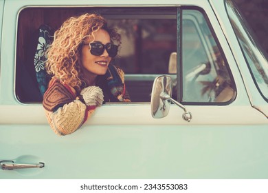 Vintage travel style image concept lifestyle. One cheerful happy woman enjoy destination sitting inside her blue classic van looking outside from the window. Freedom and alternative vehicle journey - Powered by Shutterstock