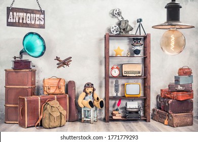 Vintage travel suitcases, backpack, old gramophone, TV, radio, mic, projector, clock, typewriter, quill, books, camera, Teddy Bear, toy plane, signboard, mask. Antiques collectibles. Retro style photo