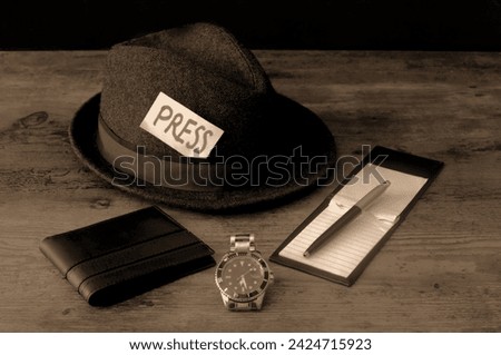 Vintage trilby reporters hat with watch and notepad and pen in sepia.