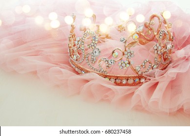 Vintage tulle pink chiffon dress and diamond tiara on wooden white table. Wedding and girl's party concept. Glitter overlay