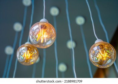 Vintage tungsten filament multiple lamps hanging from the ceiling on a white wires as an interior design concept. Energy and design concept - Shutterstock ID 2188981709
