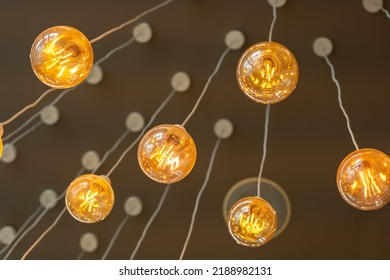 Vintage tungsten filament multiple lamps hanging from the ceiling on a white wires as an interior design concept. Energy and design concept - Shutterstock ID 2188982131