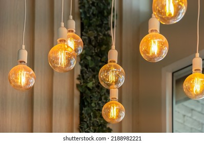 Vintage tungsten filament multiple lamps hanging from the ceiling on a white wires as an interior design concept. Energy and design concept - Shutterstock ID 2188982221